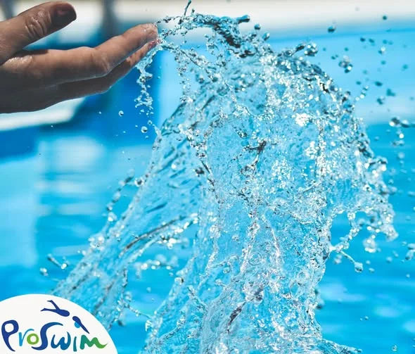 Dłoń rozbryzguje strumień wody nad niebieską taflą basenu