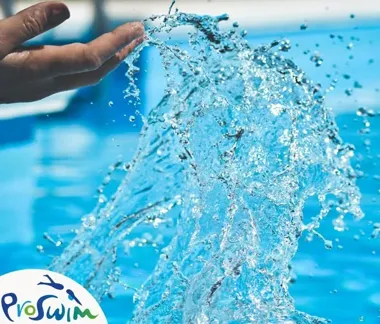 Dłoń rozbryzguje strumień wody nad niebieską taflą basenu