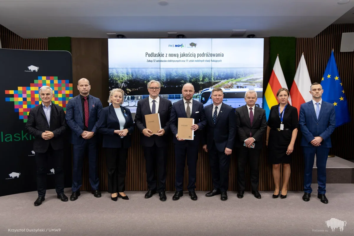 Grupa osób podczas uroczystości podpisania umowy na zakup autobusów elektrycznych i mobilnych stacji ładujących dla Podlaskiego.