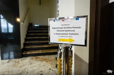 Tabliczka informacyjna wskazująca kierunek do sali spotkania Regionalnego Komitetu Rozwoju Ekonomii Społecznej w Województwie Podlaskim, ustawiona w holu z marm