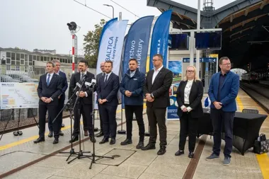 Grupa osób stoi na peronie kolejowym podczas konferencji prasowej dotyczącej projektu Rail Baltica.